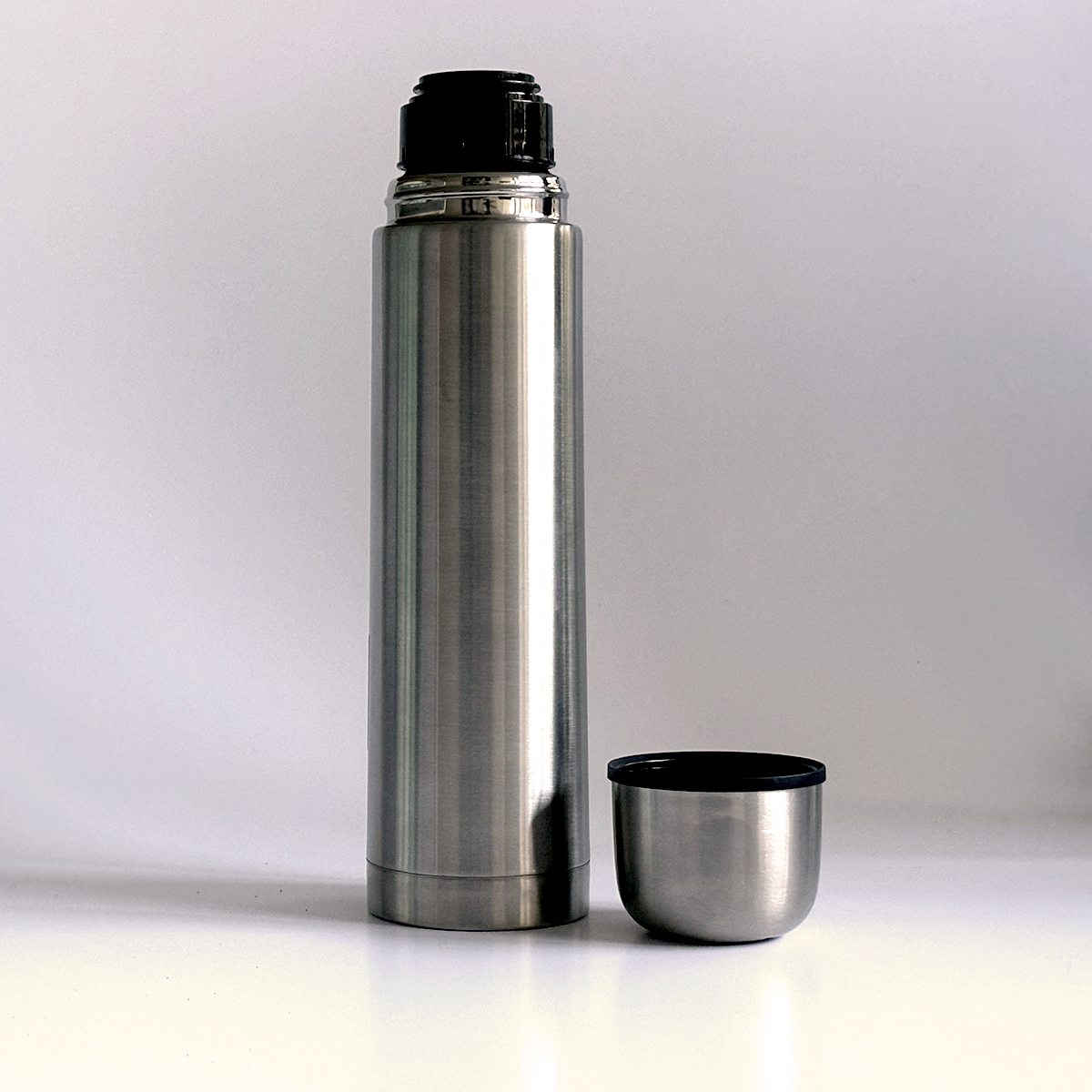 Edelstahl-Thermoskanne mit abgenommenem Deckel, der als Becher dient.