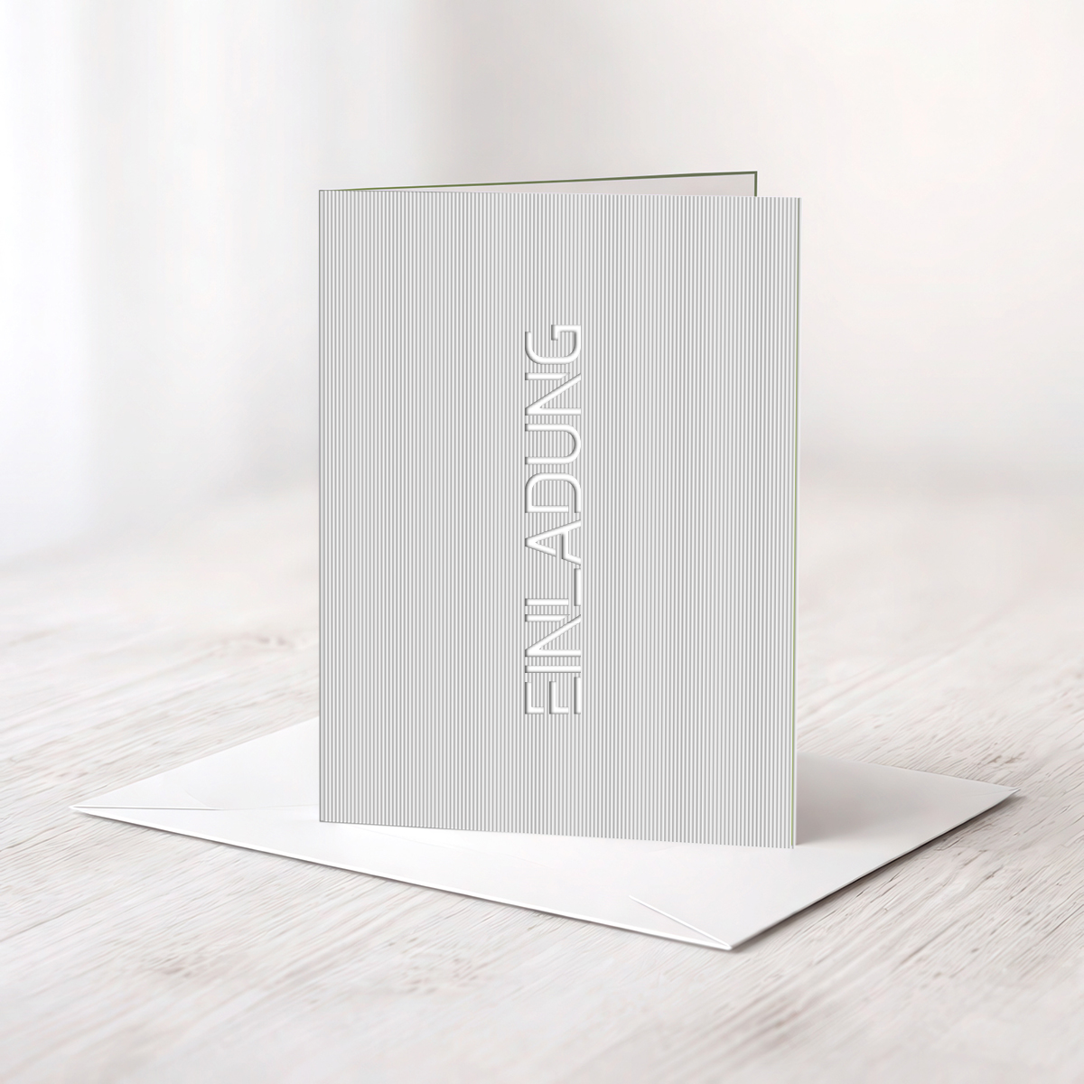 Gelaserten Schriftzug „Einladung“ in silbernem Riffelkarton